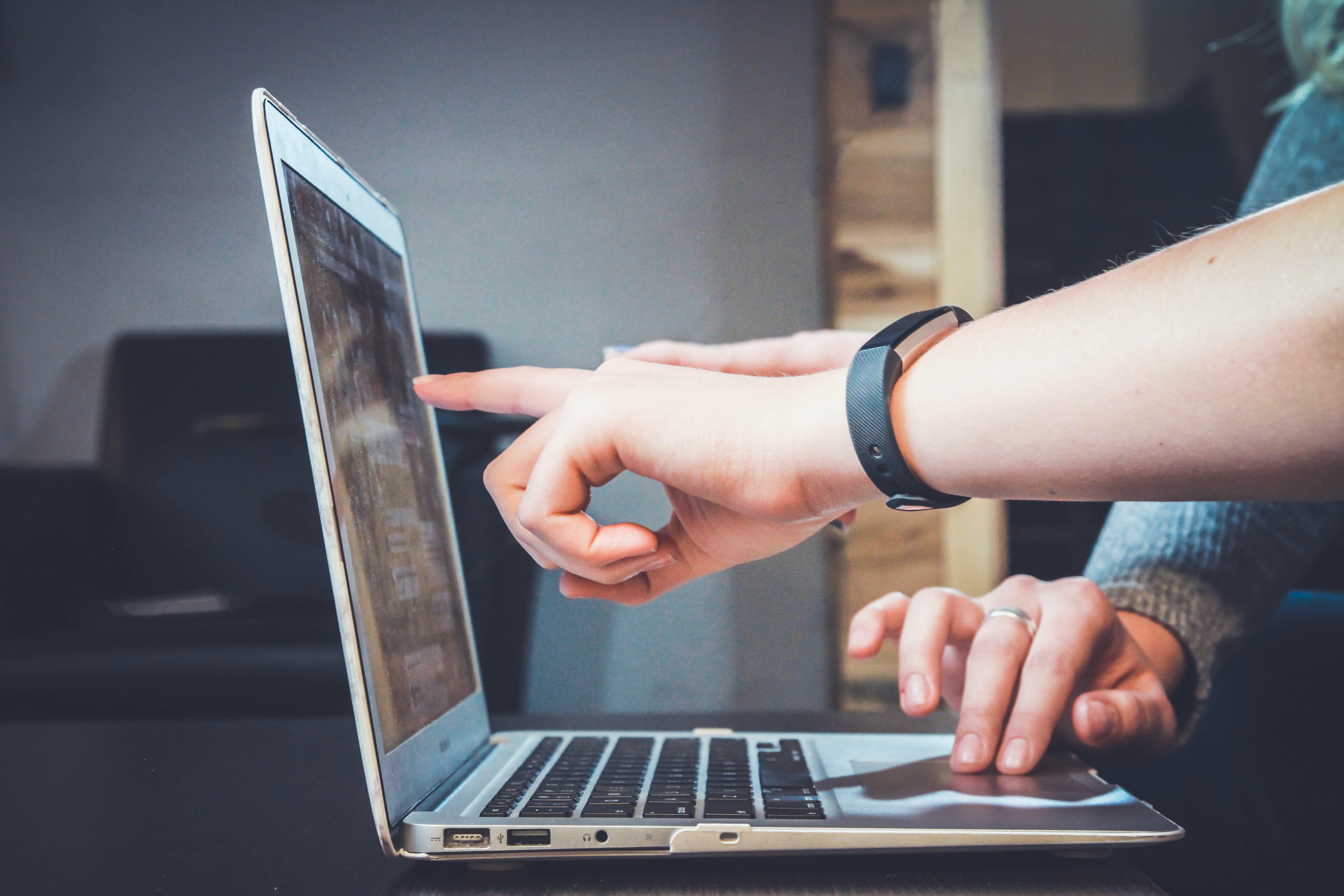 Photo of people's finger pointing to a computer screen